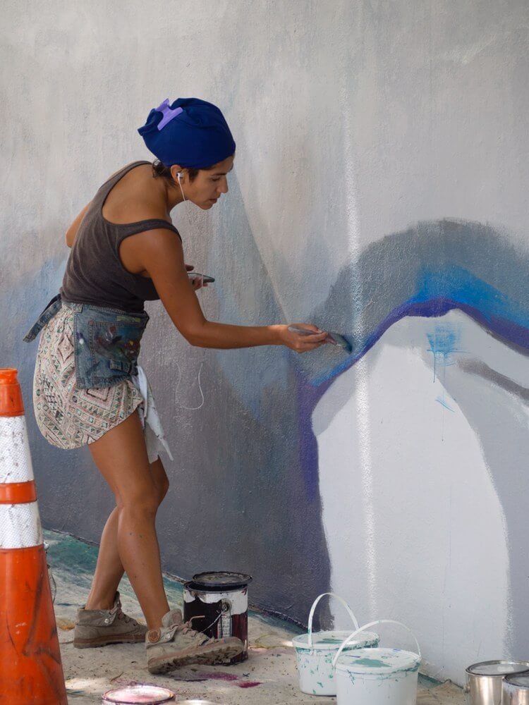 Cat Ferraz painting a mural in Hollywood, Fla.