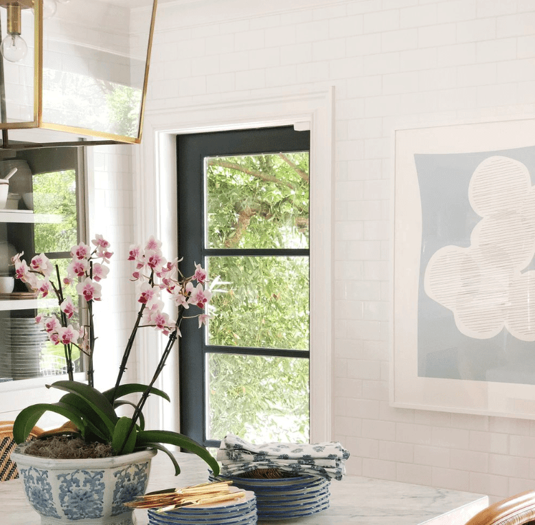 Abstract art of overlapping rounded shapes in white on a blueish-gray background in a white frame in a kitchen.