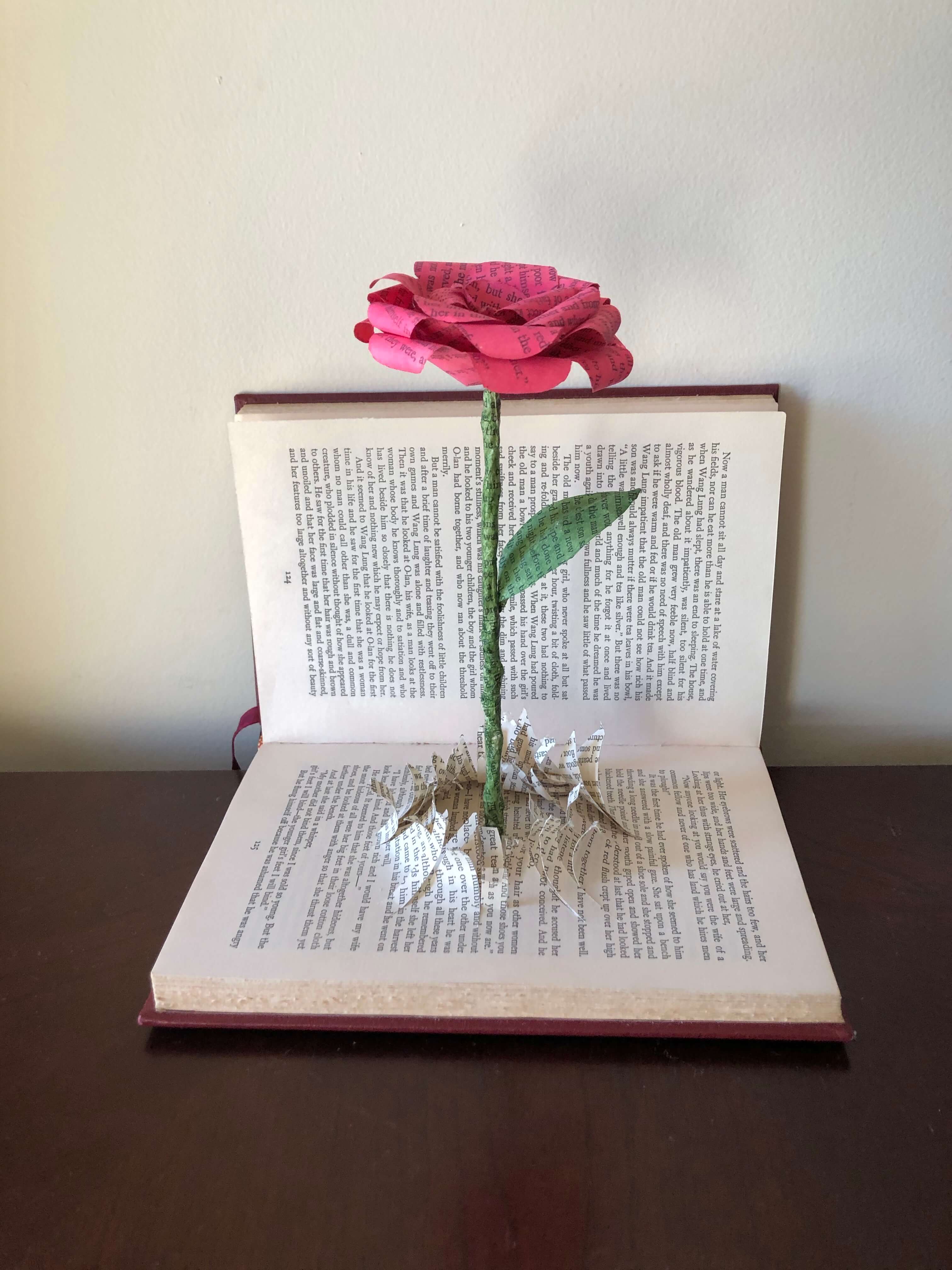 In this paper art, a rose, created from the pages of the same damaged book, appears to have burst through the publication. 