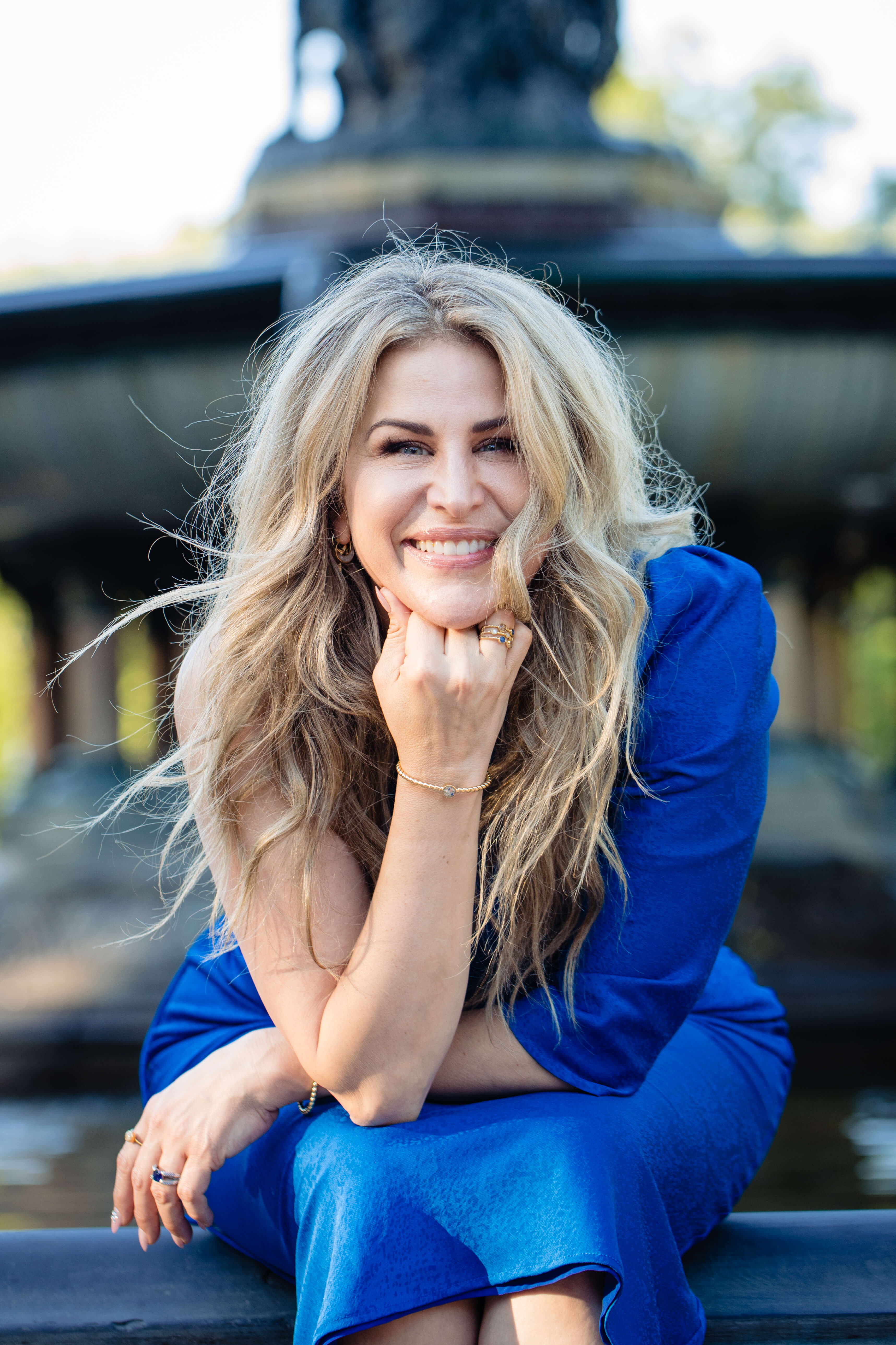 Photo of Holly Daniels Christensen. She has long blonde hair with beachy waves and is wearing a blue dress. 