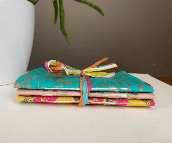 Idea for handmade gifts for Mother's Day: Image shows 3 handmade notebooks tied in raffia ribbon,