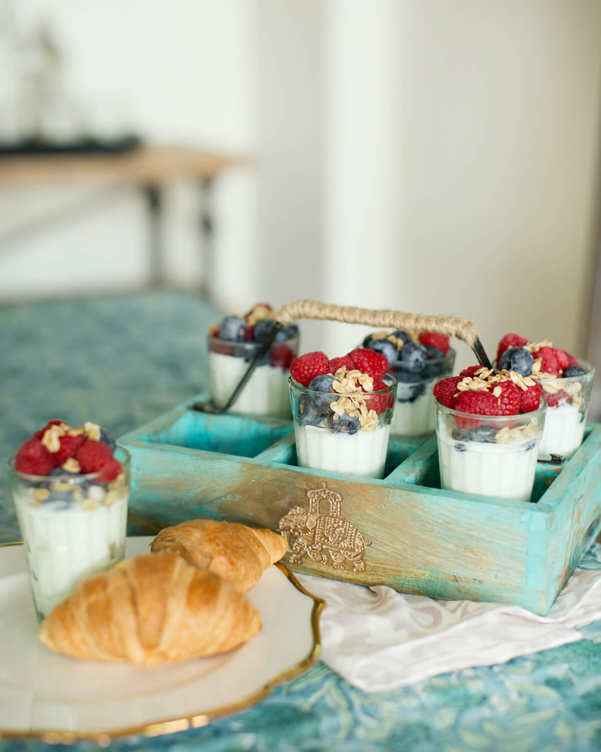 A wooden tray in robin's egg blue. The tray features 6 compartments and the picture shows it holding yogurt parfaits in glassware.  Designed by Sushmitha Pidatala of Arjuna Design Studio.