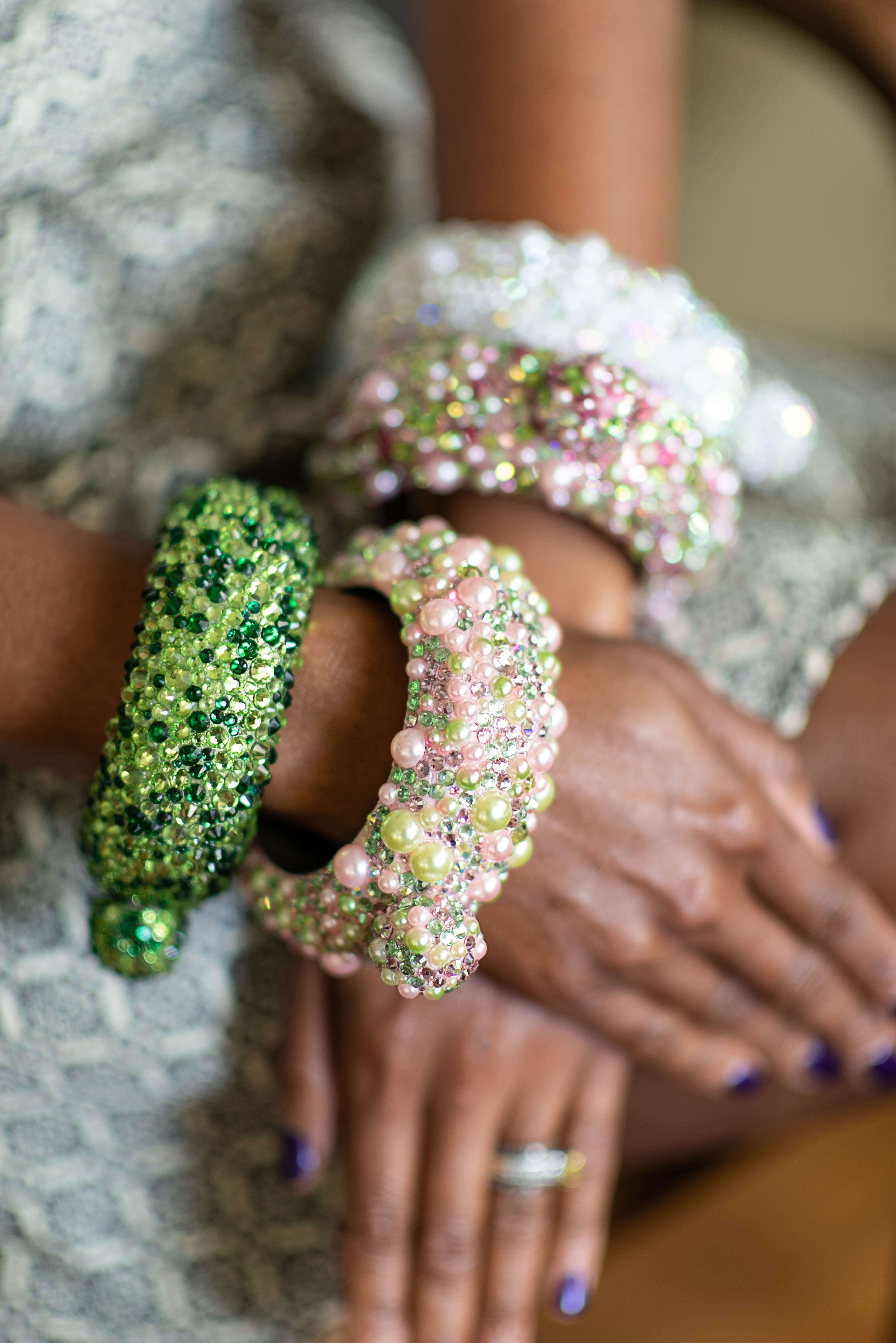 A photo of four bedazzled cuff bracelets in white, green and pink and green.