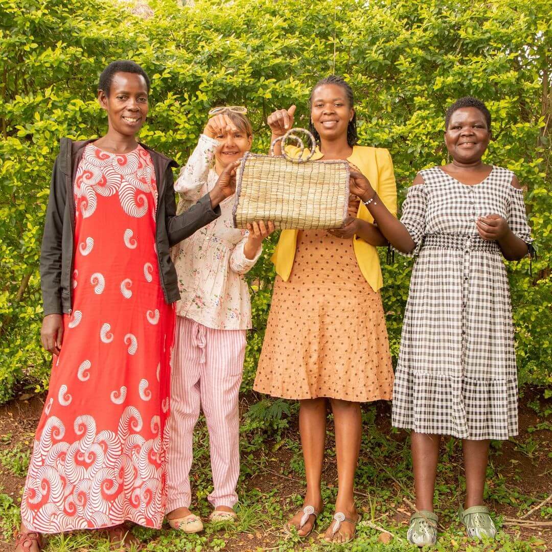 Social enterprise entrepreneur Margarida Vasconcelos and artisan weavers from Seeds & Stories posing with a handbag.